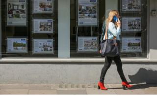 woman walks past estate agent