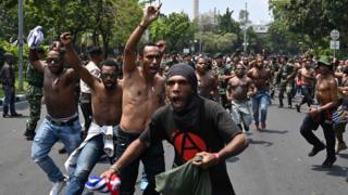 Protesters in Jakarta break away from the military in the background, who are unable to control them