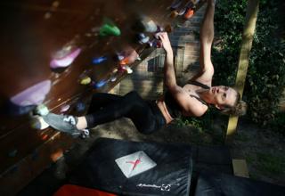 A climber hangs from an outdoor climbing wall