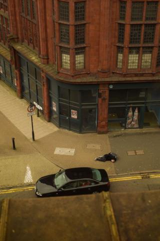 A view onto a street pavement showing a man lying on the ground
