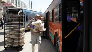 Bakers load bread onto buses for distribution in Jordan’s capital, Amman