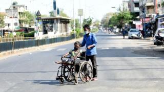 Un homme pousse une femme sur un fauteuil roulant alors qu'ils portent des masques lors d'un verrouillage national imposé par le gouvernement