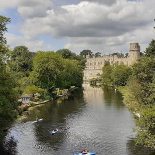 People kayaking on the River Avon, with Warwick Castle in the background