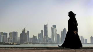 Mulher, vestida com burca, caminha em Doha