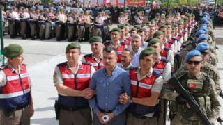 Айыпталуучулардын катарынан тизип алып сот залына алып келе жаткан учурда президент Реджеп Тайип Эрдогандын жактоочулары чогулуп турушту.