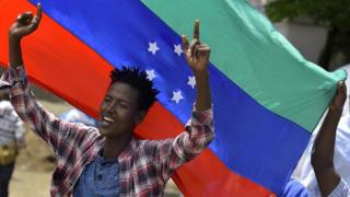 A protester waves the unofficial turquoise blue and red Sidama flag