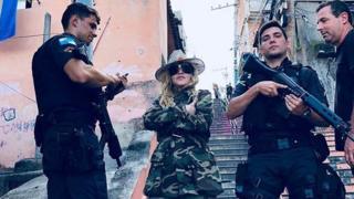 Madonna poses with military police wielding guns in a Rio de Janeiro slum.