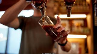 Homem segura copo de cerveja