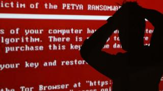A silhouetted figure against a ransomware screenshot