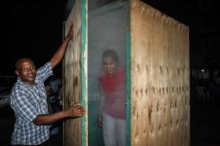 A woman is shrouded in steam as she leaves an inhalation booth installed by a Tanzanian herbalist.