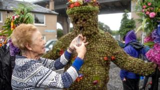 Burryman Andrew Taylor is given whisky through a straw by local resident Mary Hamblin