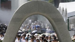 People offer prayers for victims of the atomic bombing in front of a cenotaph at Hiroshima Peace Memorial Park (06 August 2015)