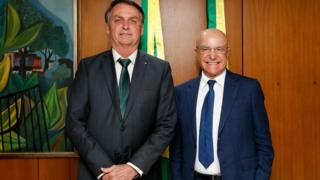 Bolsonaro e Salim Mattar posam para foto, sorrindo, de dentro de sala