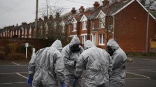 Military in protective clothing prepare to remove vehicles from a car park in Salisbury