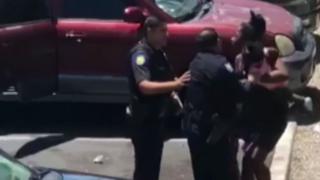 Police officers confront a woman holding a baby