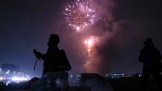 Journalists film as fireworks explode near Tama river in Tokyo