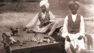 चारपाई पर चीते के साथ बैठे दो लोग