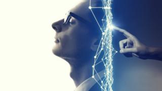 Hombre con los ojos cerrados mientras alguien programa desde atrás su cerebro.