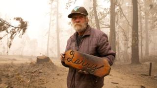 Man with plaque left from his destroyed cabin