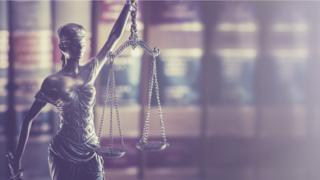 Small statue of Justice in front of legal books