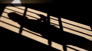 A shadow is cast of a cell door
