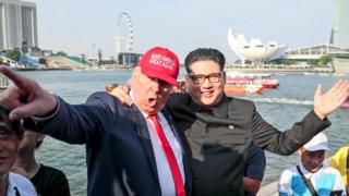 Президент США Дональд Трамп, имитатор Денниса (слева) и лидер Северной Кореи Ким Чен Ын, имитатор Говарда (C-R), изображены на фоне «Флаер Сингапура» и «Марина Бэй» во время позирования для фотографов в Сингапуре, 8 июня 2018 года Дональд Трамп едет в Сингапур из Канады, где он участвовал в капризном саммите G7
