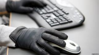Hands with black gloves on computer keyboard and mouse