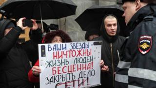 Protester holding a sign supporting the Set defendants outside FSB