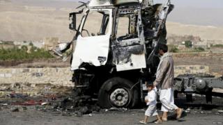 A man and his son walk past a truck hit by a Saudi-led air strike in Yemen"s northwestern province of Amran