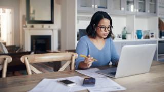 Technology A woman sits at a desk working from home