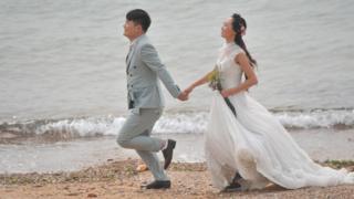 A couple take wedding photos by the sea at the Eight Great Passes (aka Ba Da Guan) on October 12, 2016 in Qingdao, Shandong Province of China