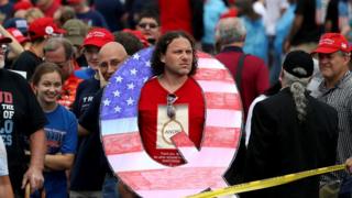 Man poses with a Q sign at a Trump rally