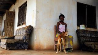 A woman sits with her dog outside her house on the outskirts of Yaounde, Cameroon, 9 October 2018.