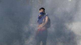 Joven emerge entre la humareda en las protestas en Chile.
