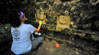 An archaeologist works cleaning the stucco of a temple in Kulubá, Yucatan state