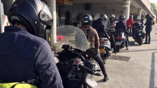 девять мотоциклистов стоят в очереди на заправочной станции
