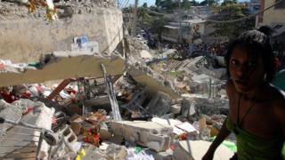 Haitians pass destroyed buildings on January 13, 2010 in Port-au-Prince, Haiti.