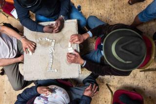 Men play dominoes at a table