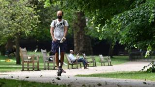 Un hombre monta una moto eléctrica por el parque de St James en el centro de Londres.