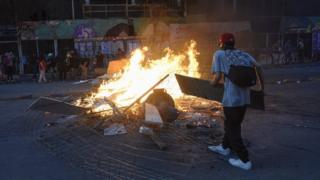 in_pictures A demonstrator makes a burning barricade during a national strike and general demonstration called by different workers' unions on 12 November, 2019 in Santiago, Chile.