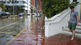 Hombre saliendo de un edificio en una calle inundada