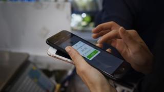 A woman making purchases through her smartphone at a shop in Beijing on 23 July 2017