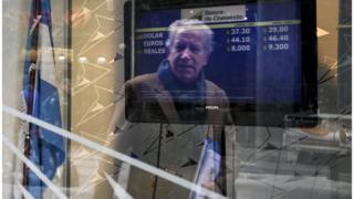 أرجنتيني يطالع سعر صرف البيزو مقابل عملات أجنبية في مكتب للصرافة