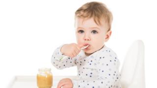 Toddler eating a jar of baby food