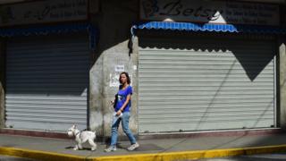 A woman passes by closed stores in Caracas, on October 28, 2016