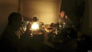 Ravshan, a Crimean Tatar, is reflected in a mirror as he eats by the light of a burning oil lamp due to a power cut inside his house in the village of Strogonovka, Simferopol district, Crimea, in this November 26, 2015 file photo