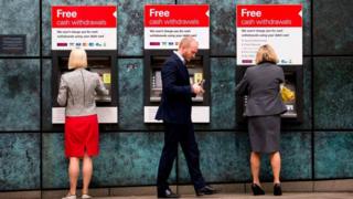 Customers use ATM cashpoints outside a HSBC bank branch in London