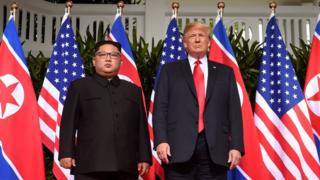 Президент США Дональд Трамп (справа) позирует с лидером Северной Кореи Ким Чен Уном (слева) на старте своего исторического саммита США-Северная Корея