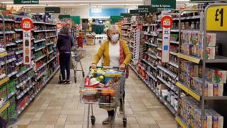 A woman in a face mask shops in a supermarket in St Albans, England.
