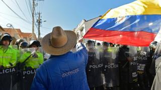 Manifestante en Ecuador agita bandera de su país frente a grupo de policías.
